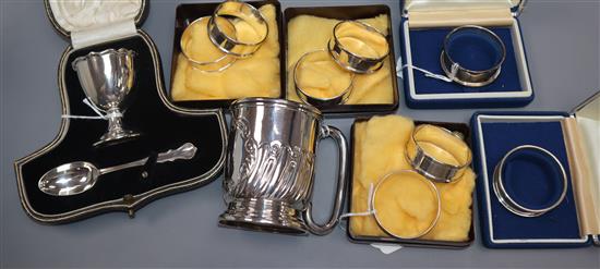 A silver Christening egg cup and spoon set, cased, a half-wrythen silver Christening mug and four pairs of silver napkin rings,